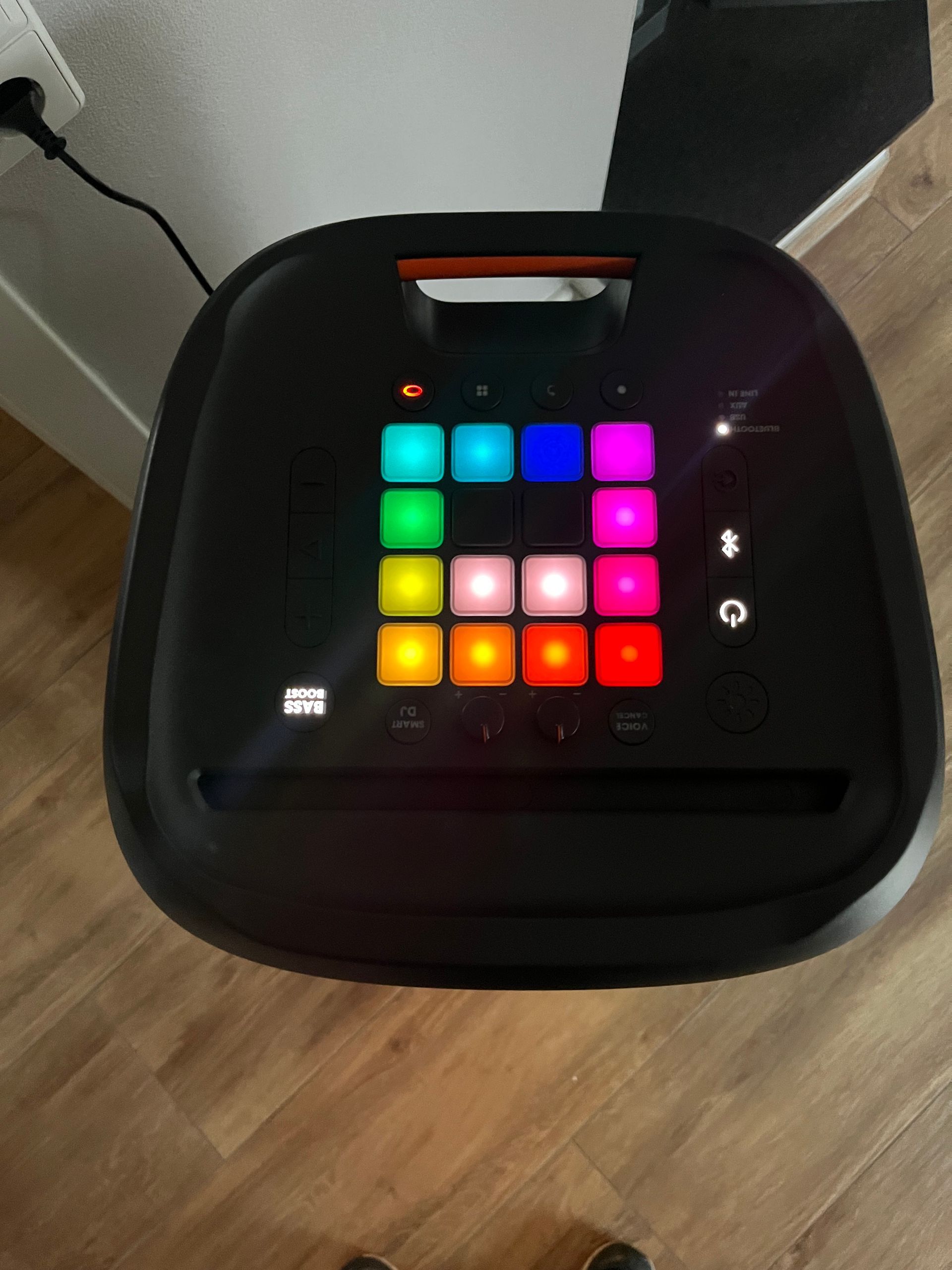 Draufsicht auf das Bedienfeld eines JBL PartyBox-Lautsprechers mit einem farbenfrohen, beleuchteten 4x4-Raster aus Tasten.