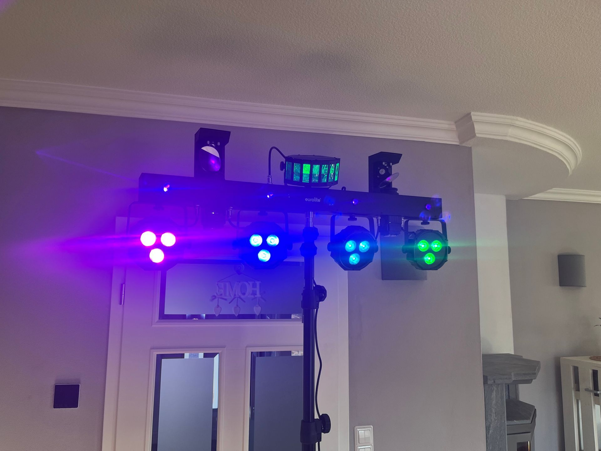 Eine Bühnenbeleuchtungsanlage mit vier farbigen LED-Scheinwerfern und einem zentralen Lichteffekt, montiert auf einem schwarzen Stativ.