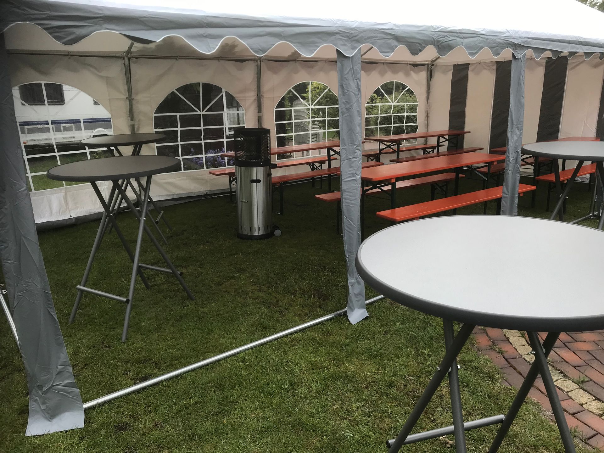 Ein im Freien auf Rasen aufgebautes Festzelt mit runden Stehtischen und langen Biergartenbänken als Sitzgelegenheiten.