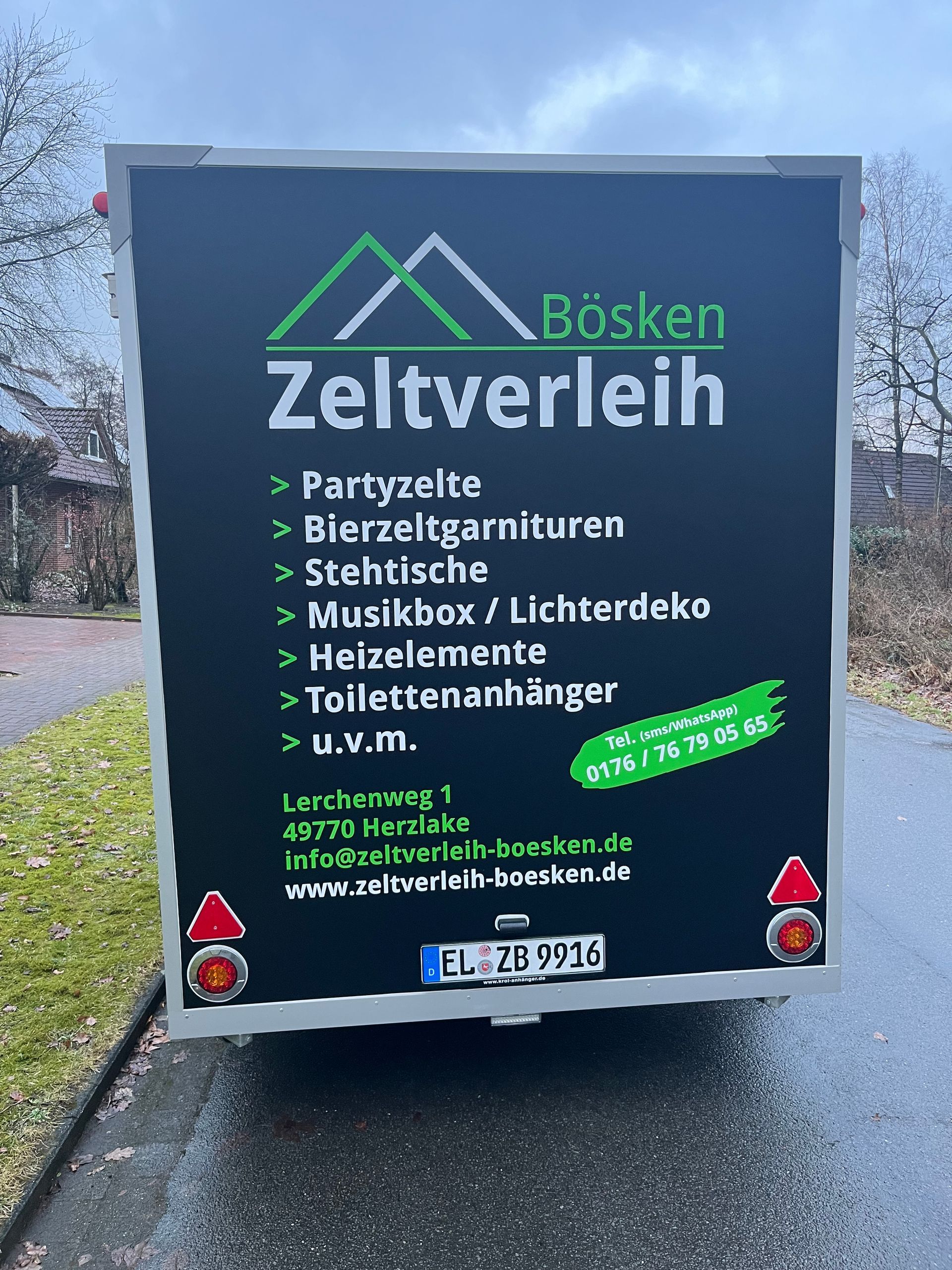 Rückansicht eines schwarzen Anhängers, der für die Vermietungsdienste, Kontaktdaten und die Website von „Bösken Zeltverleih“ wirbt.