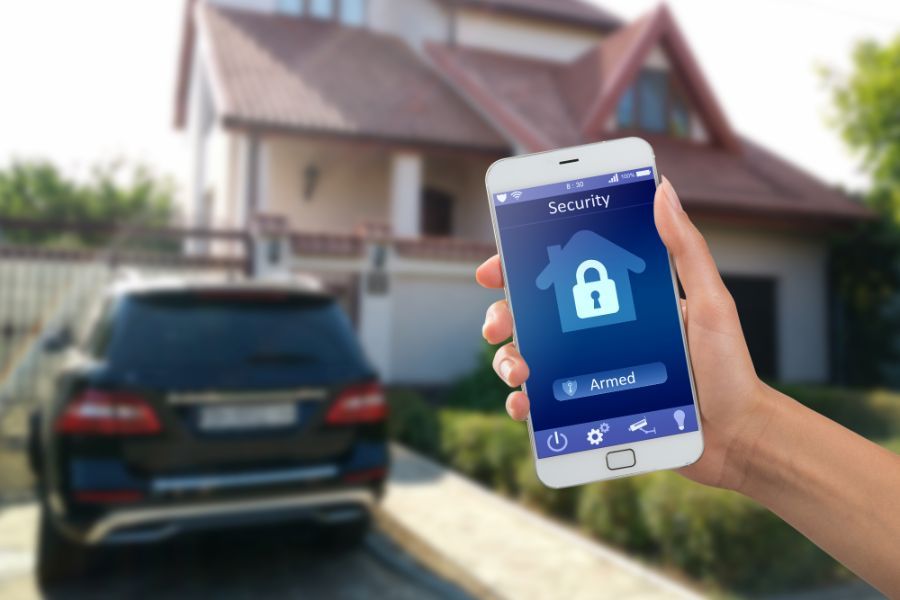 a person in front of their home with a security software app on their phone