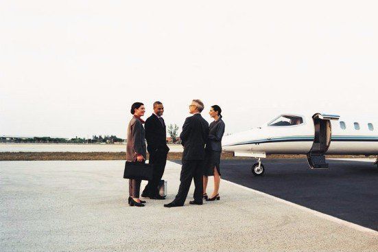 Business people waiting to board private plane after being dropped off by car service.