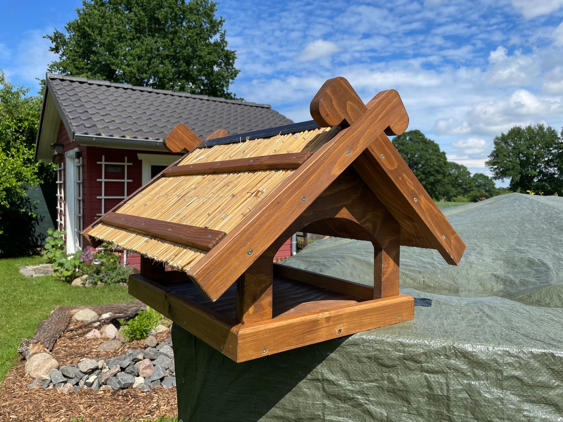 Futterhaus „Niedersachsen“ aus Holz, Dach belegt mit Schilfrohren, inklusive stilisierter Pferdeköpfe am Giebel