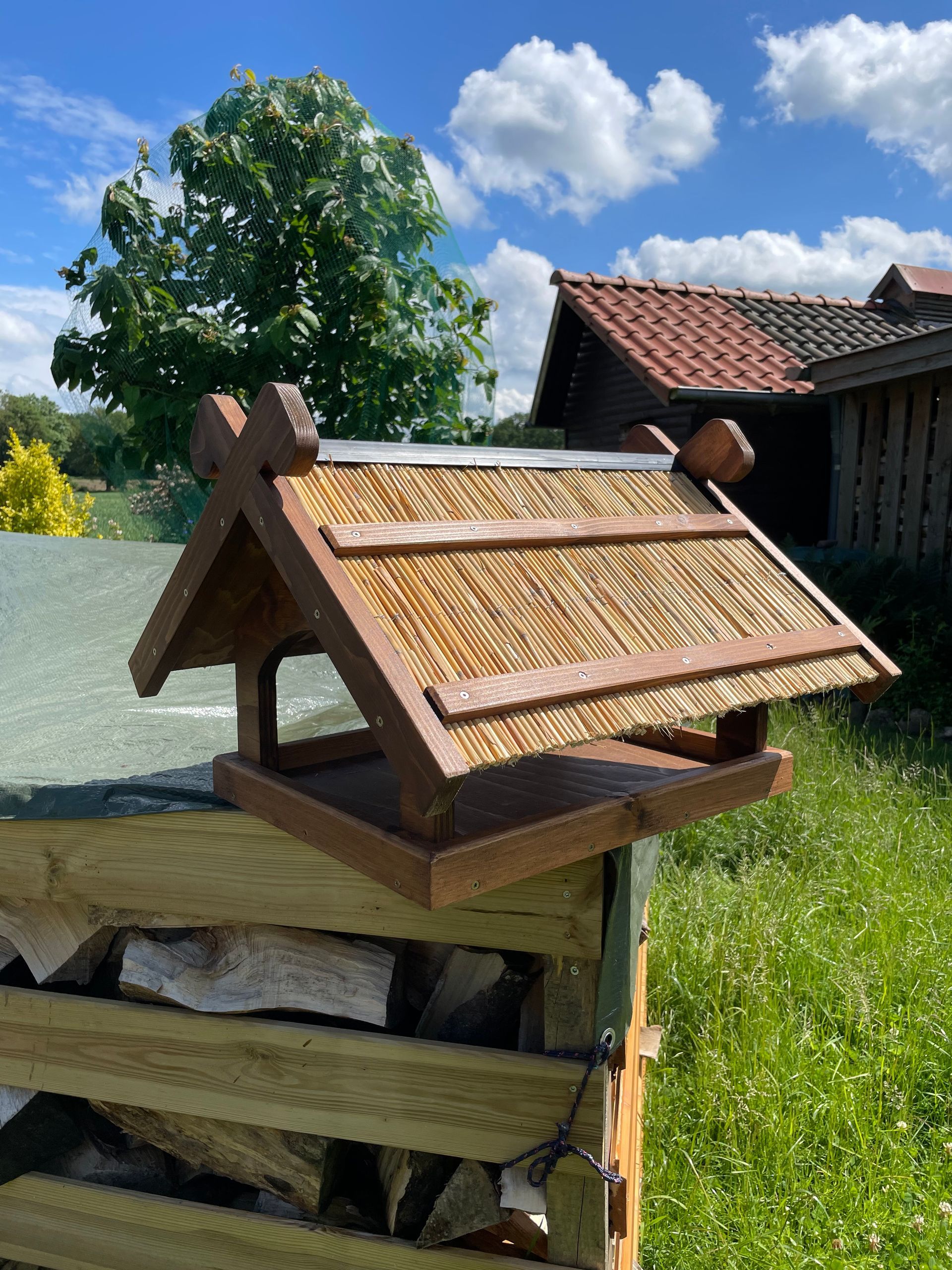 Futterhaus „Niedersachsen“ aus Holz, Dach belegt mit Schilfrohren, inklusive stilisierter Pferdeköpfe am Giebel