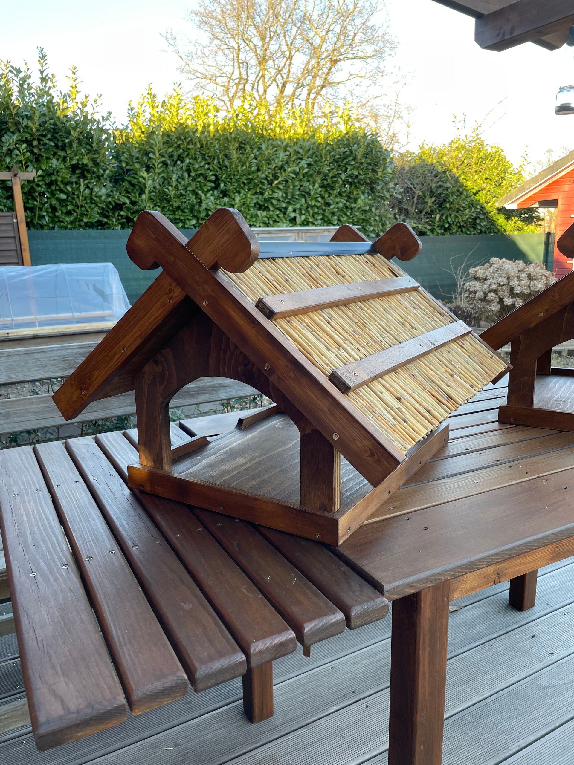 Futterhaus „Niedersachsen“ aus Holz, Dach belegt mit Schilfrohren, inklusive stilisierter Pferdeköpfe am Giebel