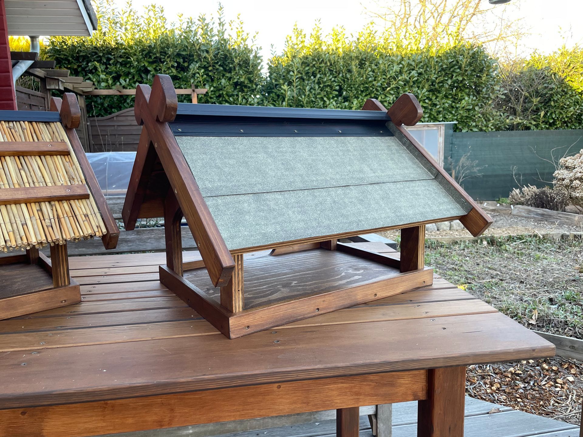 Futterhaus „Niedersachsen“ aus Holz mit Dach, belegt mit Dachpappe inklusive stilisierter Pferdeköpfe am Giebel.