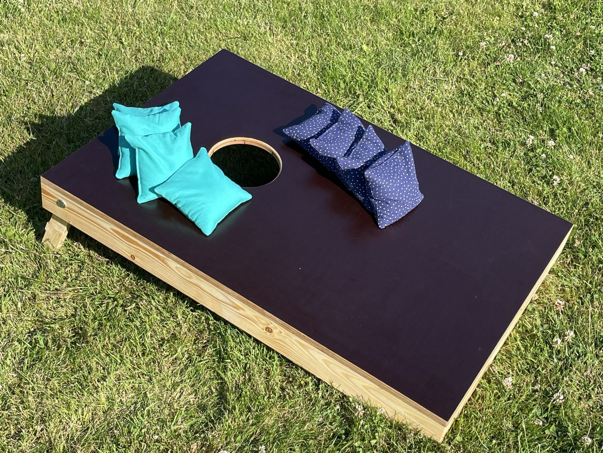 Outdoorspiel: Handgefertigtes Gesellschaftsspiel „Cornhole” auf einem Rasen stehend
