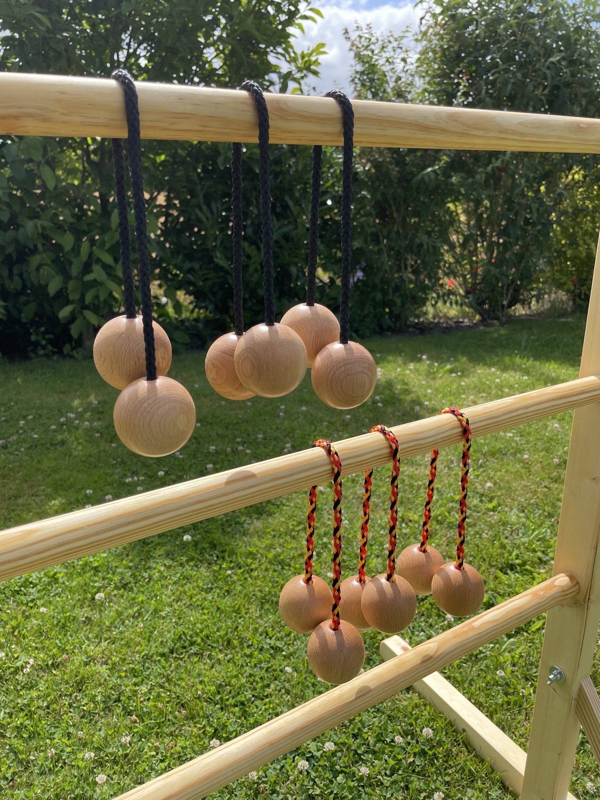 Outdoorspiel: Handgefertigtes Gesellschaftsspiel „Leitergolf” für draußen, im Fokus die Böller an einem Band „Bolas”