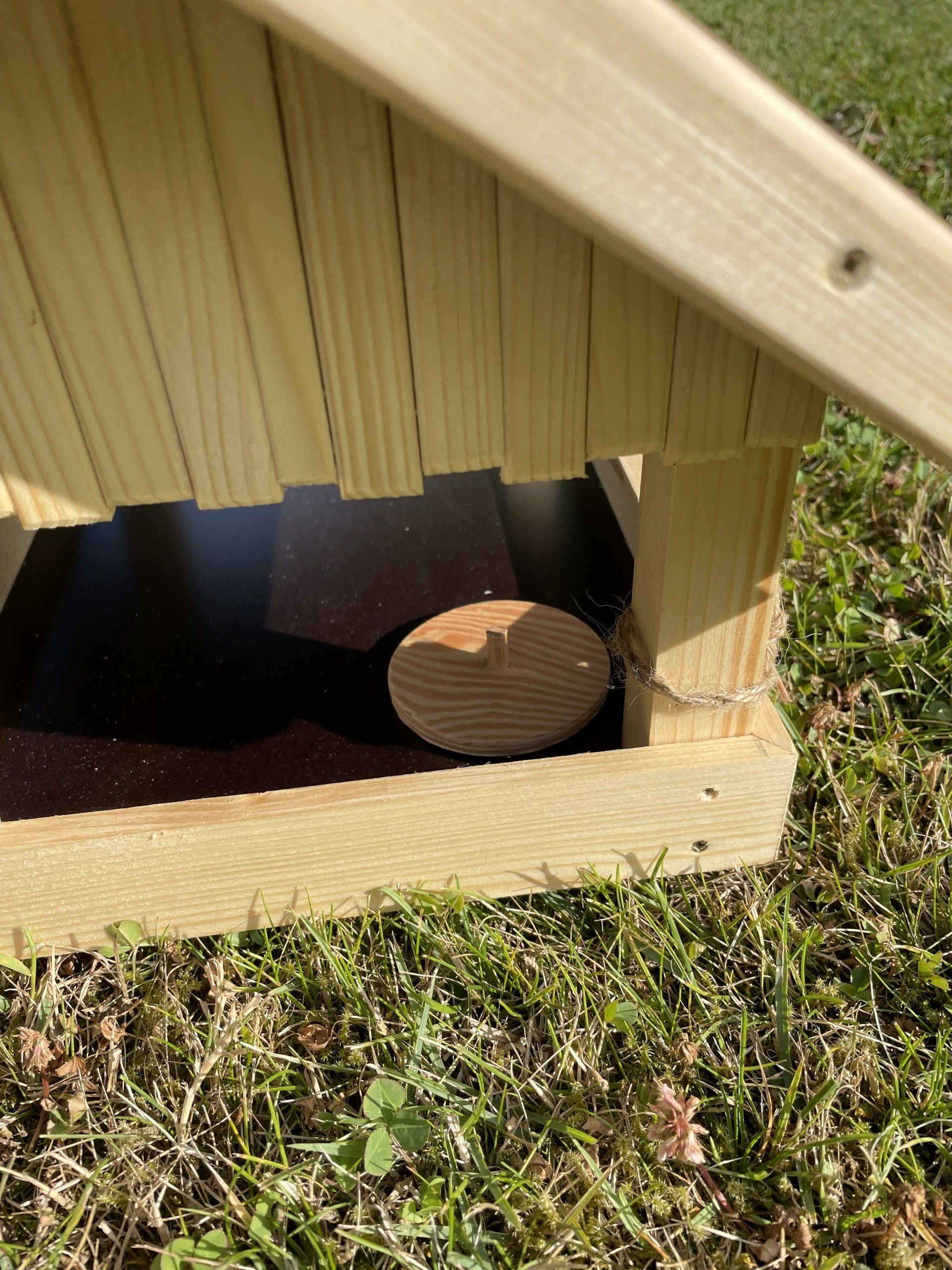 Futterhaus aus Fichtenholz mit Dach und Boden aus einer Siebdruckplatte. Fokus auf Loch und Deckel zum Säubern