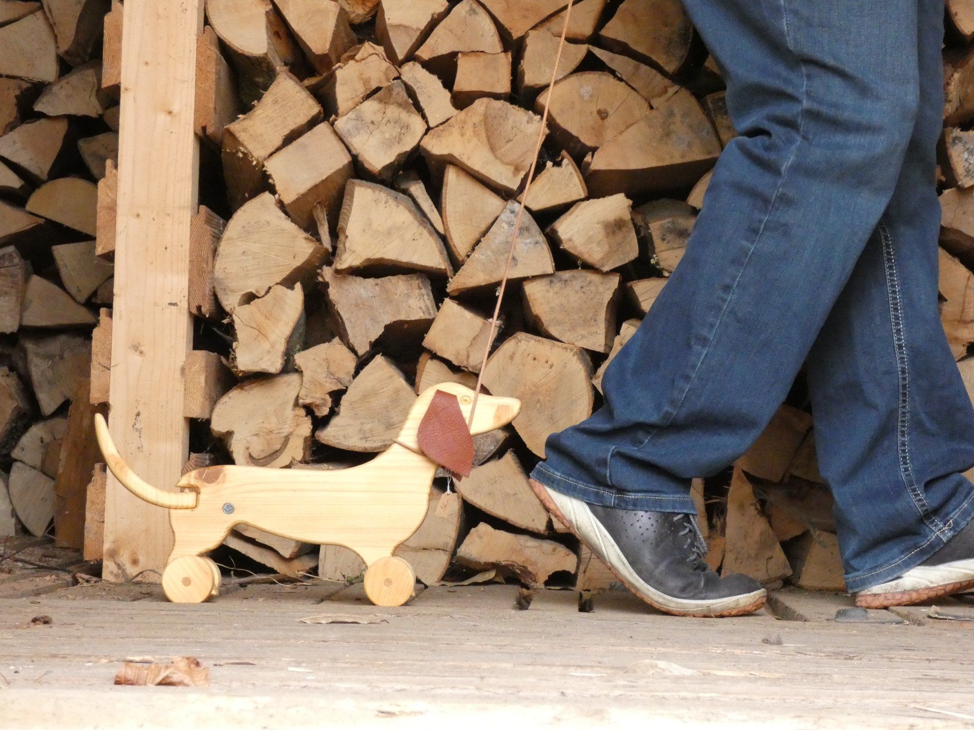 Zwei Füße die rechts aus dem Bild gehen und den handgefertigten Dackel hinter sich herziehen