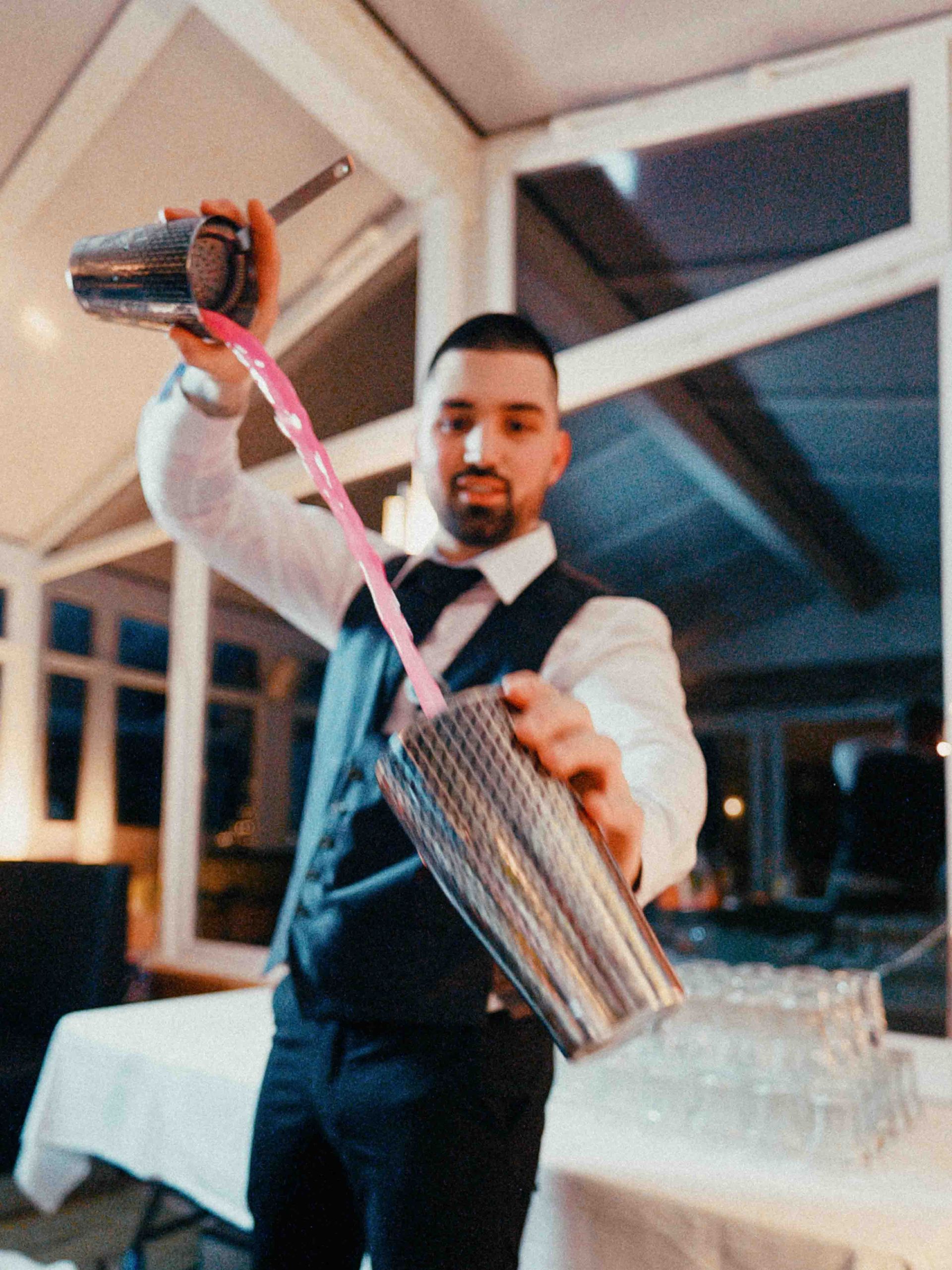 Barkeeper benutz professionelle Bartechniken um einen rosanen Cocktail zu machen