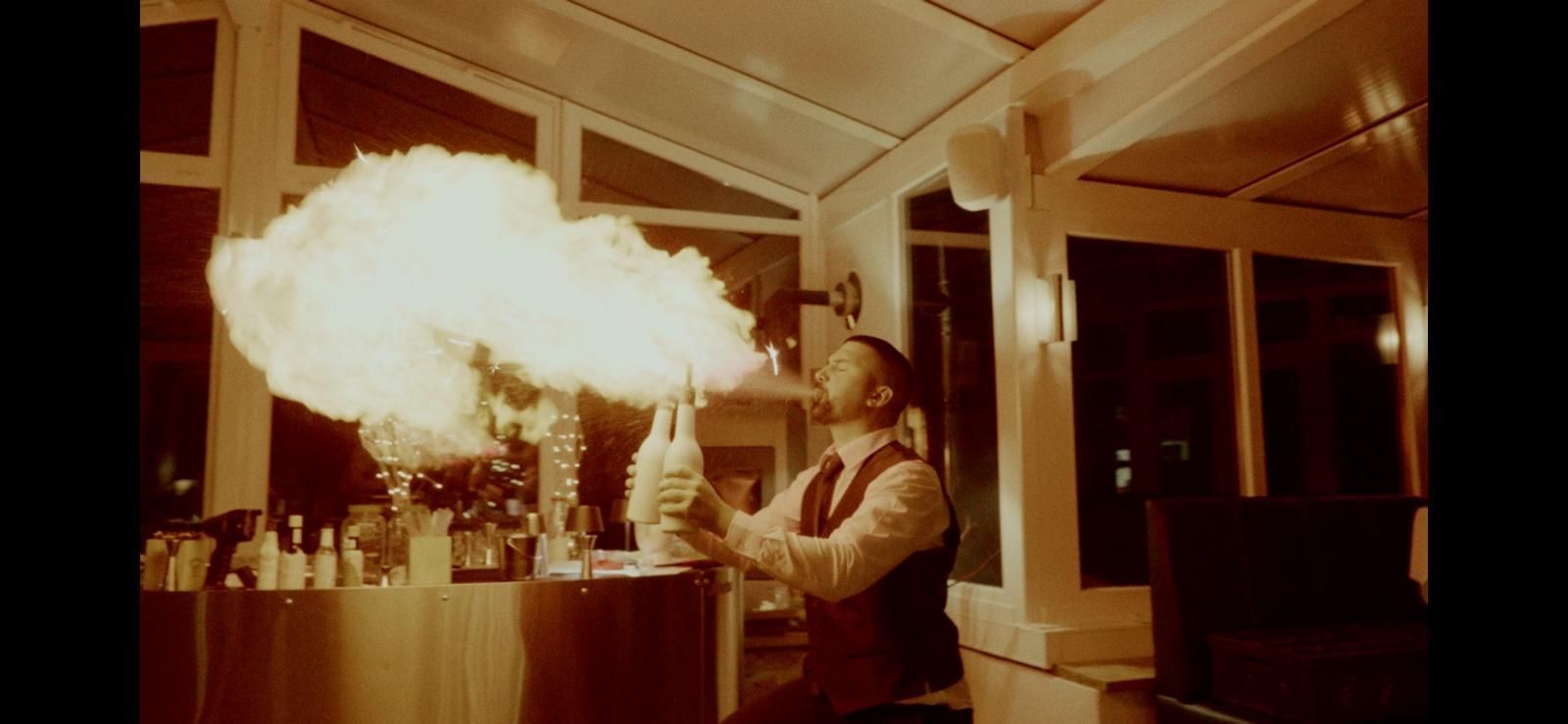 Beeindruckender Feuershow eines Flairbarkeepers mit speiendem Feuer aus dem Mund