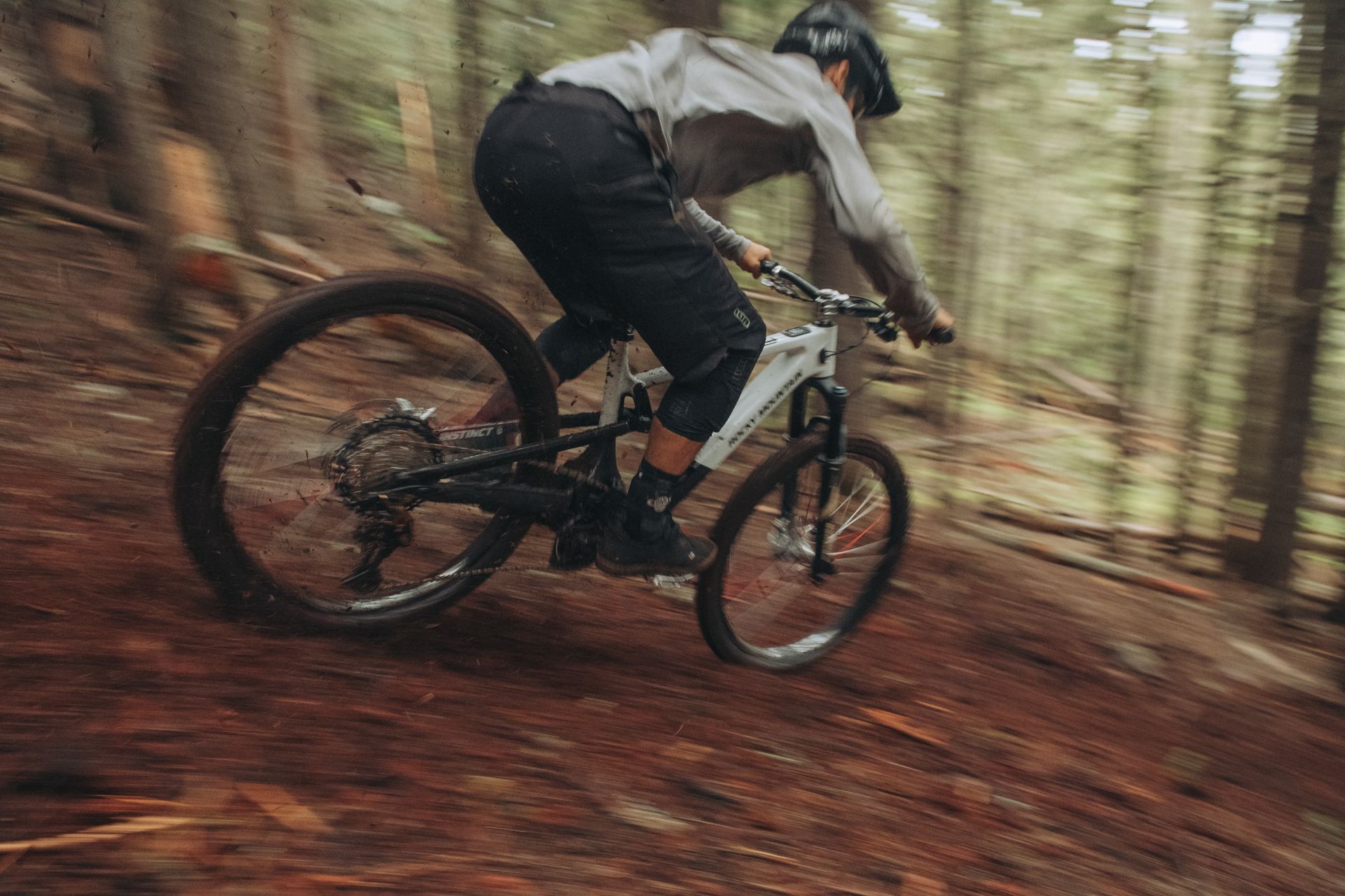 Mountainbiker fährt auf einem unbefestigten Weg im Wald bergab, verschwommene Bewegung.