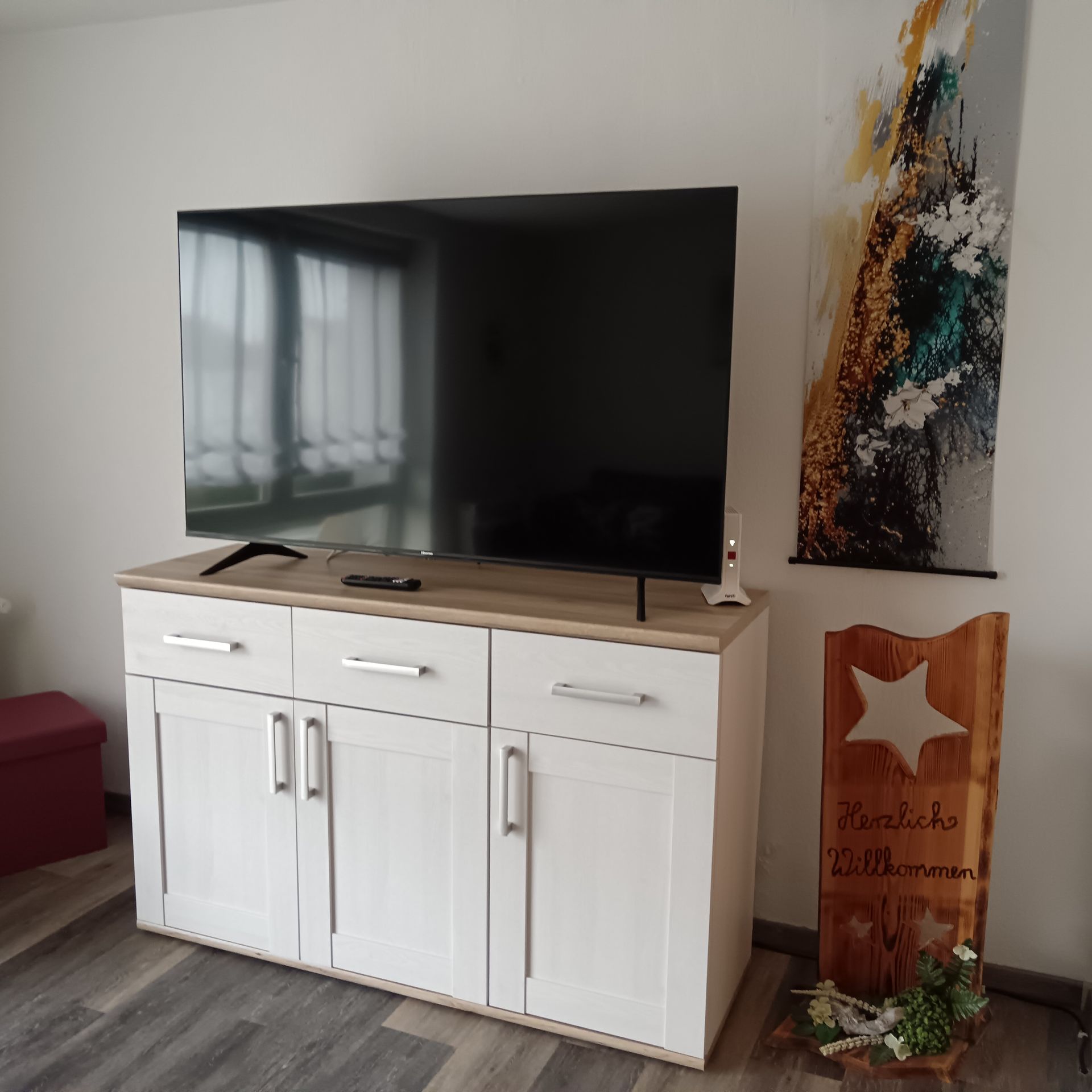 Fernseher mit LAN Anschluss, dekorativen Bildern und Willkommensschild.