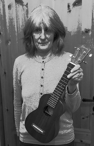 Eine Frau sieht in die Kamera. Sie hält eine Ukulele in der Hand.