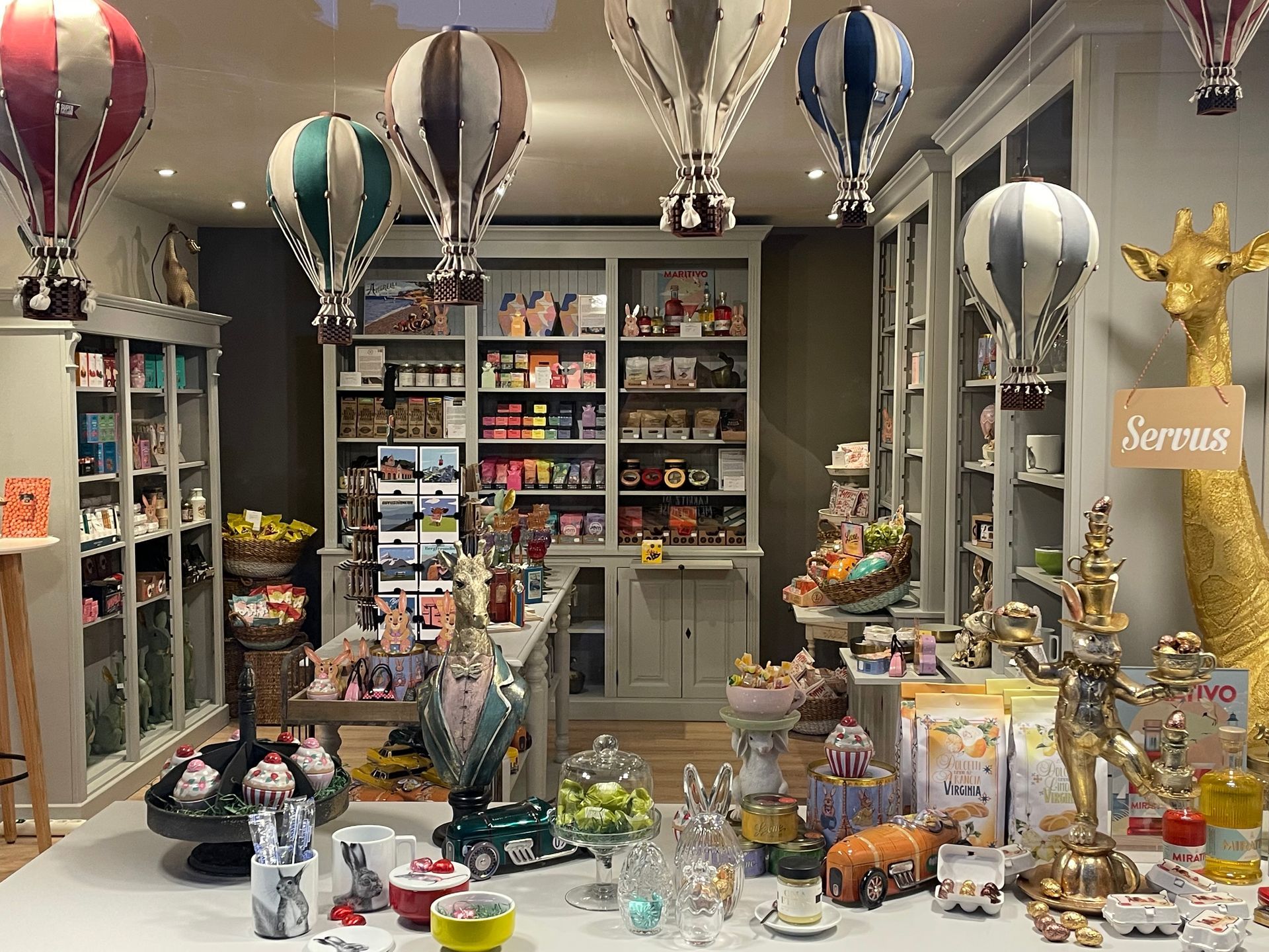 Blick in den Laden mit Regalen mit Süßigkeiten und dekorativen Figuren, Spielzeug-Heißluftballons, die von der Decke hängen.