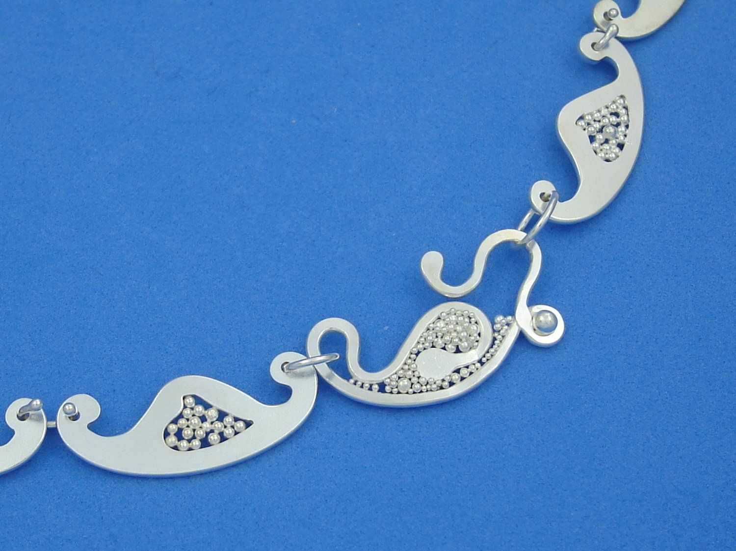 Collier aus Argentium-Sterlingsilber mit Schmuckschließe und Gliedern in Form kleiner stilisierter Schiffchen, deren mittiger Ausschnitt mit kleinen Silberkügelchen gefüllt ist