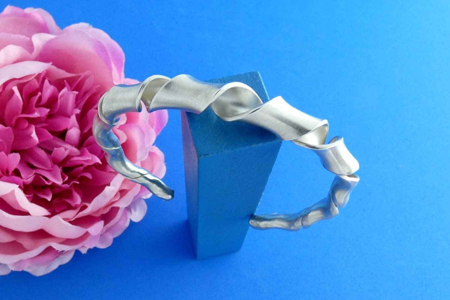 offener Armreif aus Argentium-Sterlingsilber, oval geschmiedet aus einem breiten Metallstreifen, der um die Längsachse gewunden wurde und zu den Enden hin schmal ausläuft