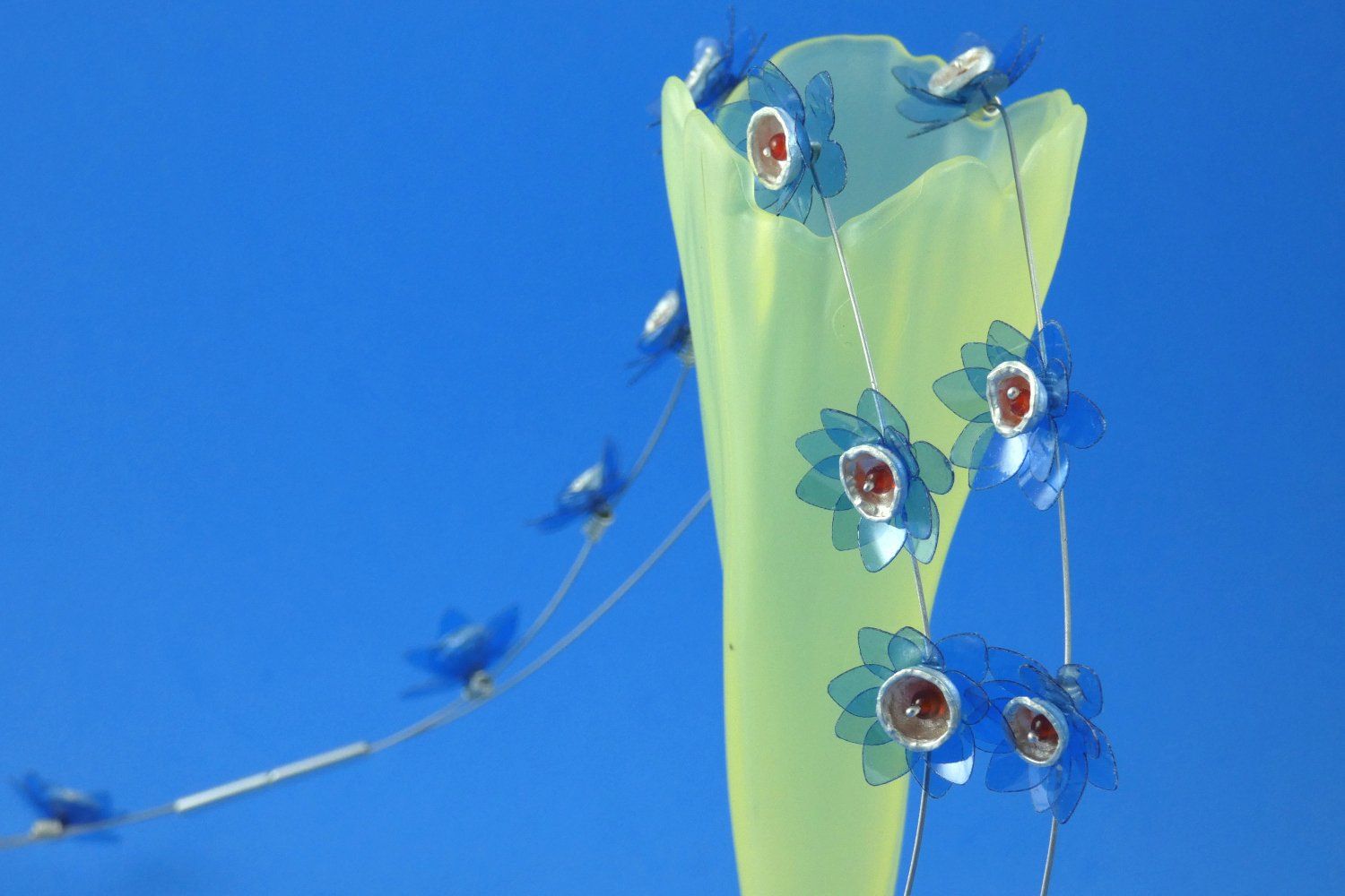 Stahlseide-Collier mit kleinen blauen transparenten Büten, die im Zentrum ein Becherchen aus Argentium-Sterlingsilber tragen, das mit einer orangeroten Carneol-Perle gefüllt ist