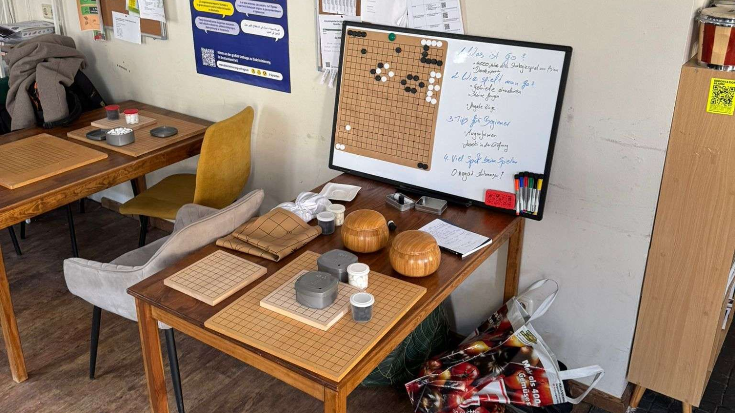 Tables set for a board game with boards, stones, and a whiteboard in a room.