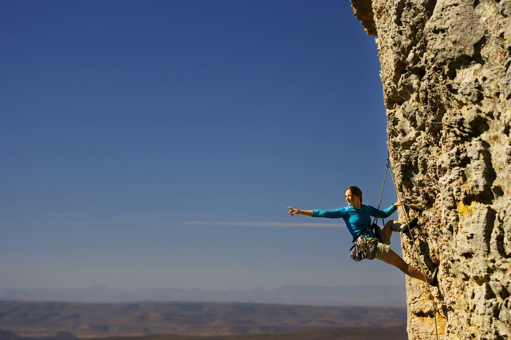 Ein Mann bei blauen Himmel klettert einen Felsen am Seil hinauf
