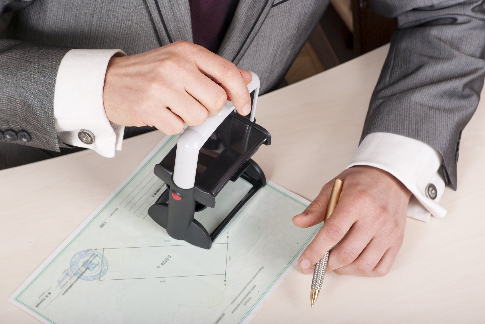 Notary's hand affixing his stamp over a contract of sale of a house in Germany