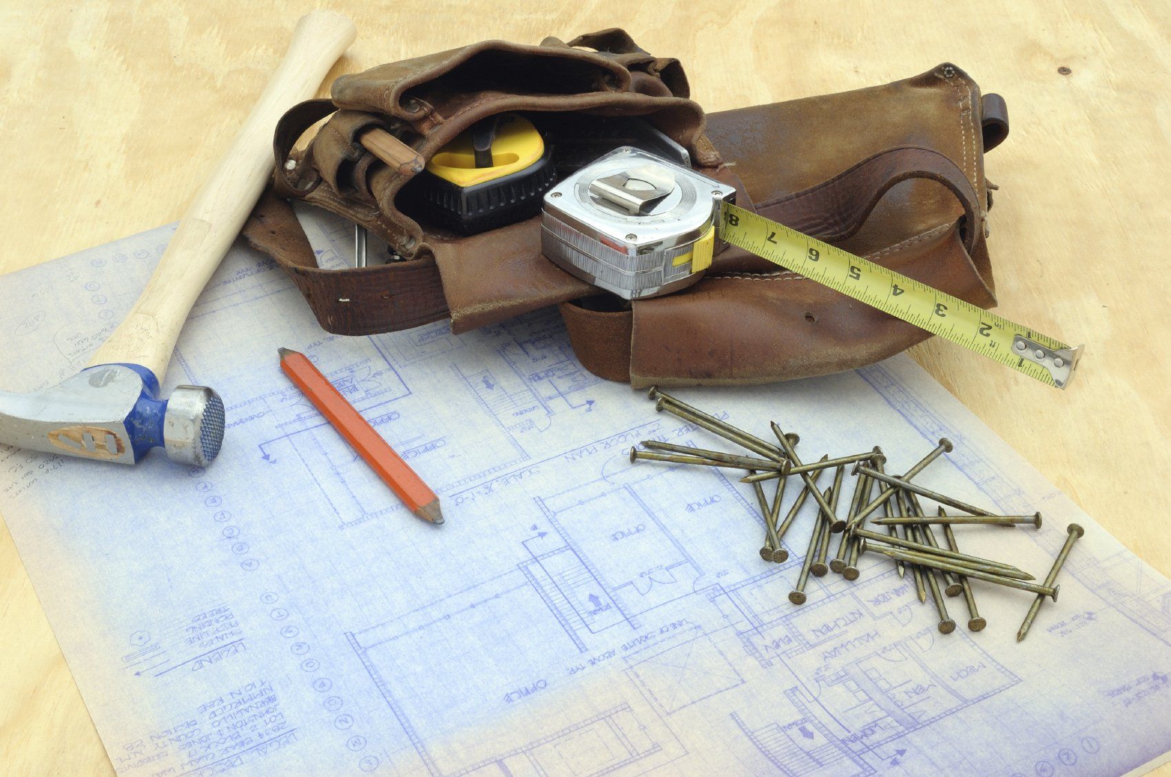 Nails, Pencil, Measuring Tape, and Belt on top of Architect Plans