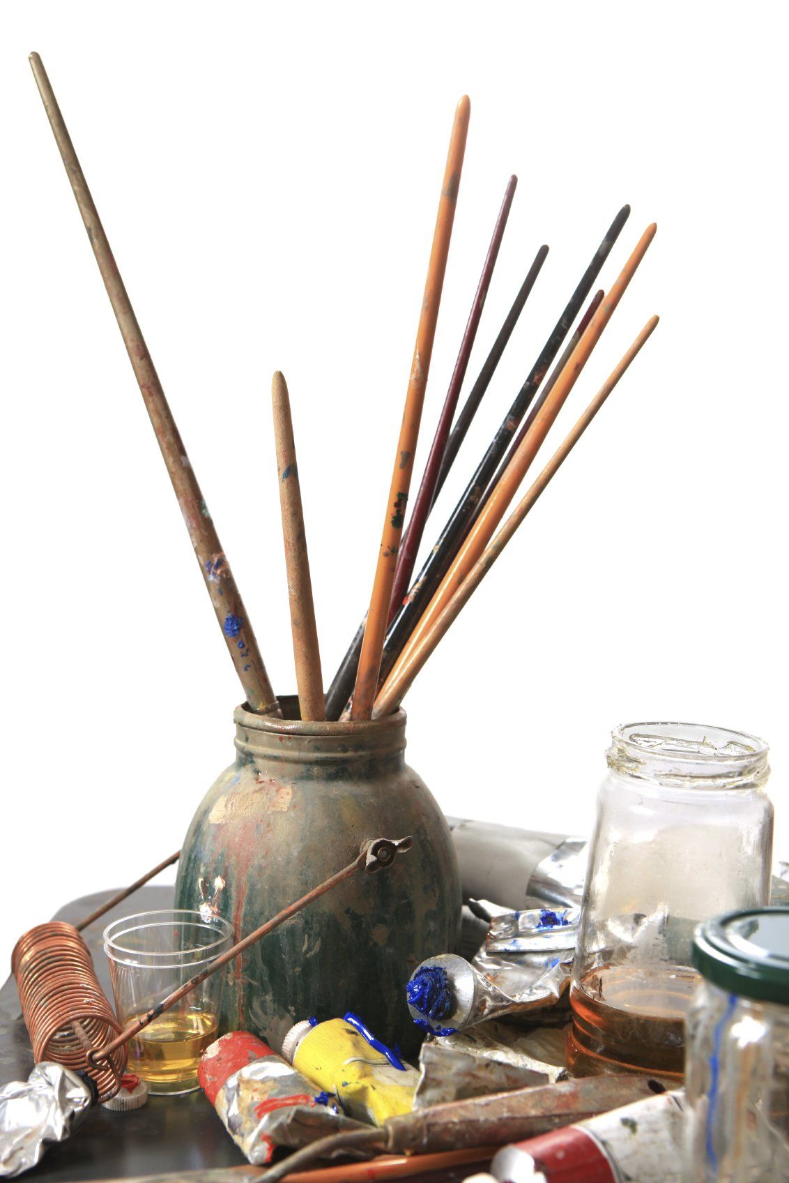 Artist's brushes sitting in a large vase surrounded by other art supplies.