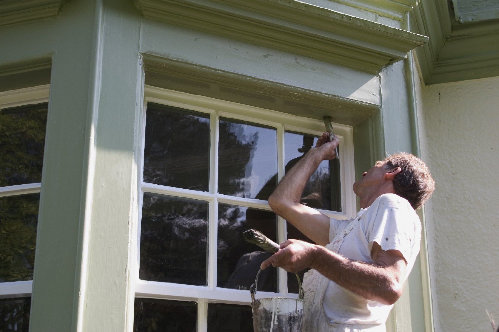 Painter painting the exterior of a house using Sherwin Williams Paint