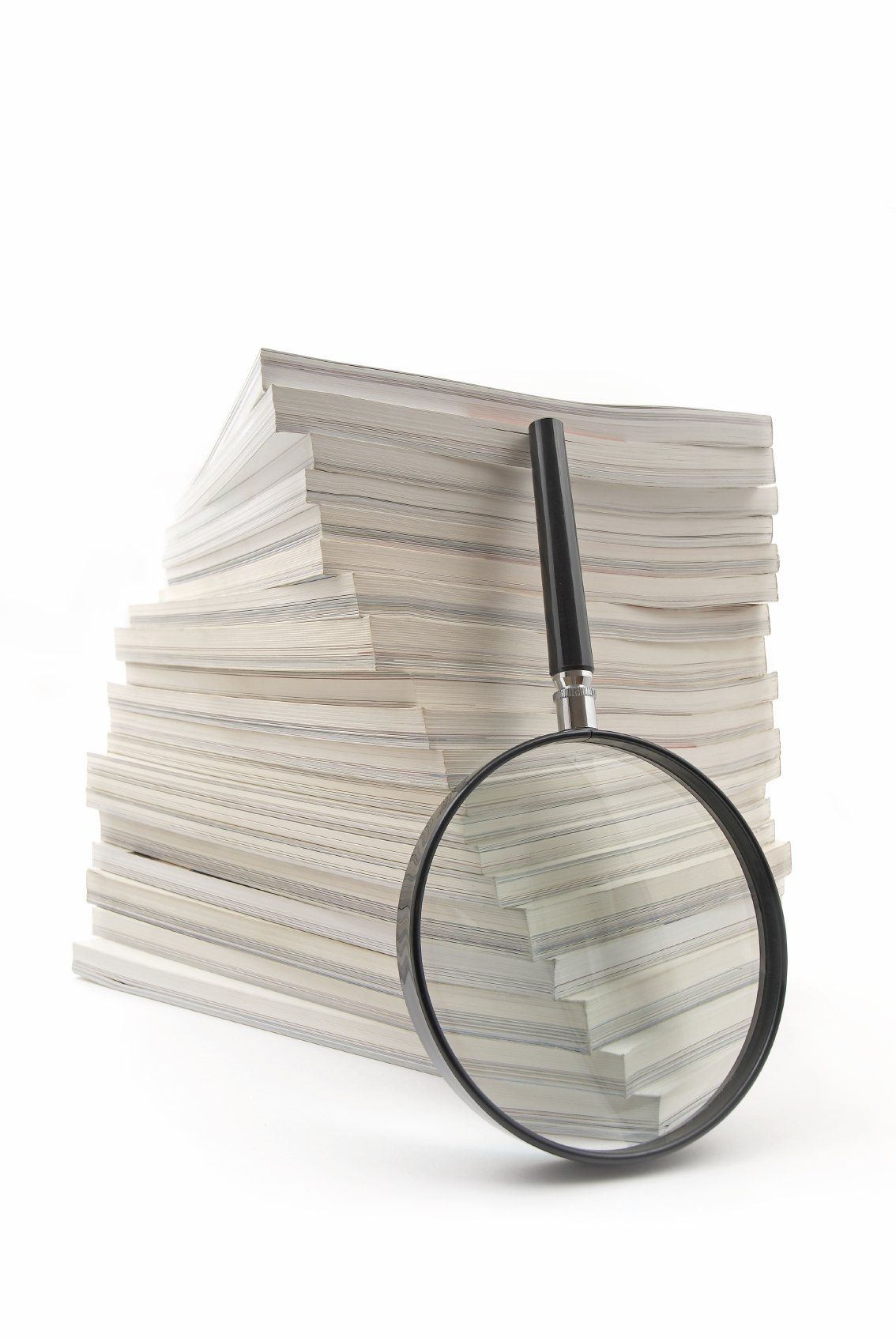 A stack of papers with a large black magnifying glass next to it.