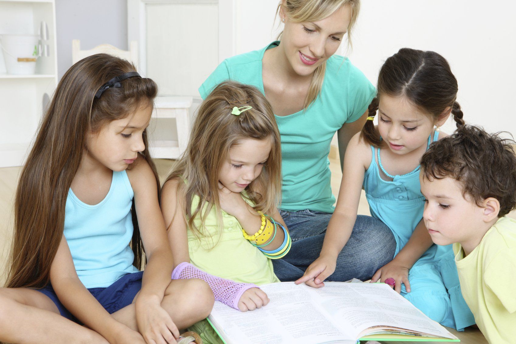 Lifelong learning: A mother and 4 little children sitting on the floor, reading a book