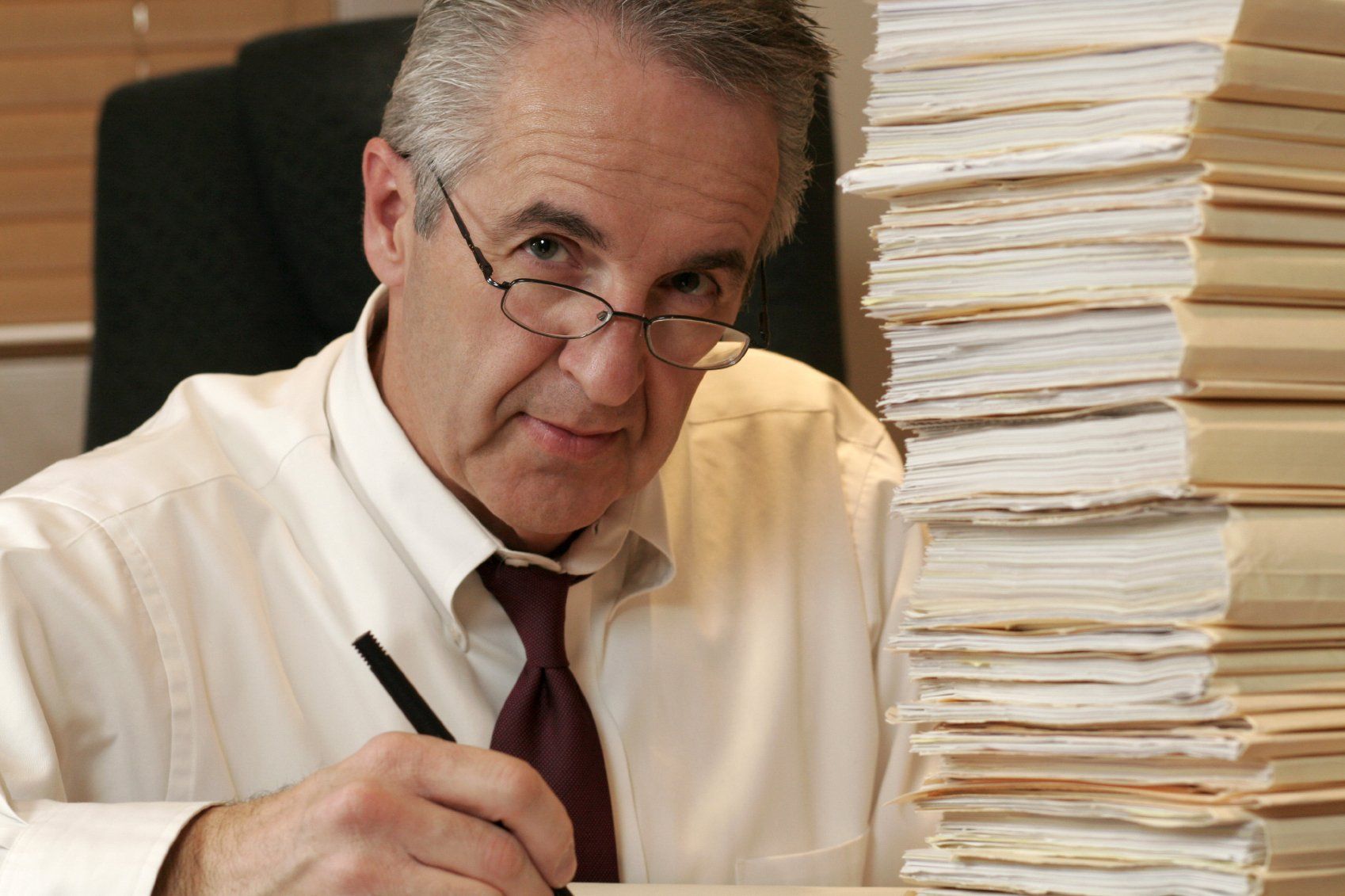 A stressed accountant at his desk, with a mountain of papers in front of him.