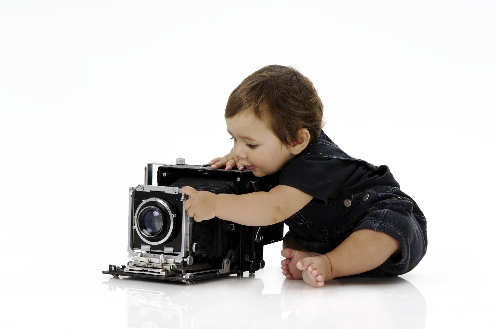 A young baby playing with an old box camera.