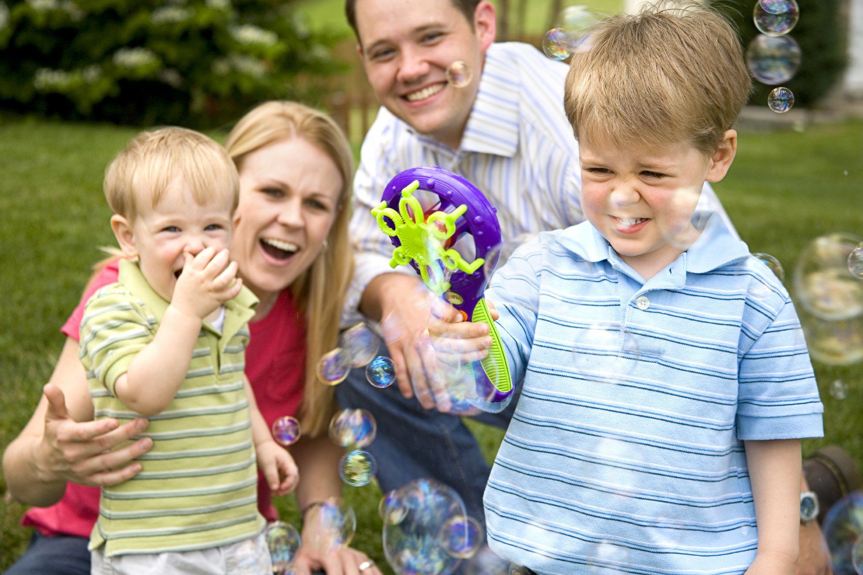 Familie mit Vater, Muter und zwei kleine Kinder im Garten am spielen