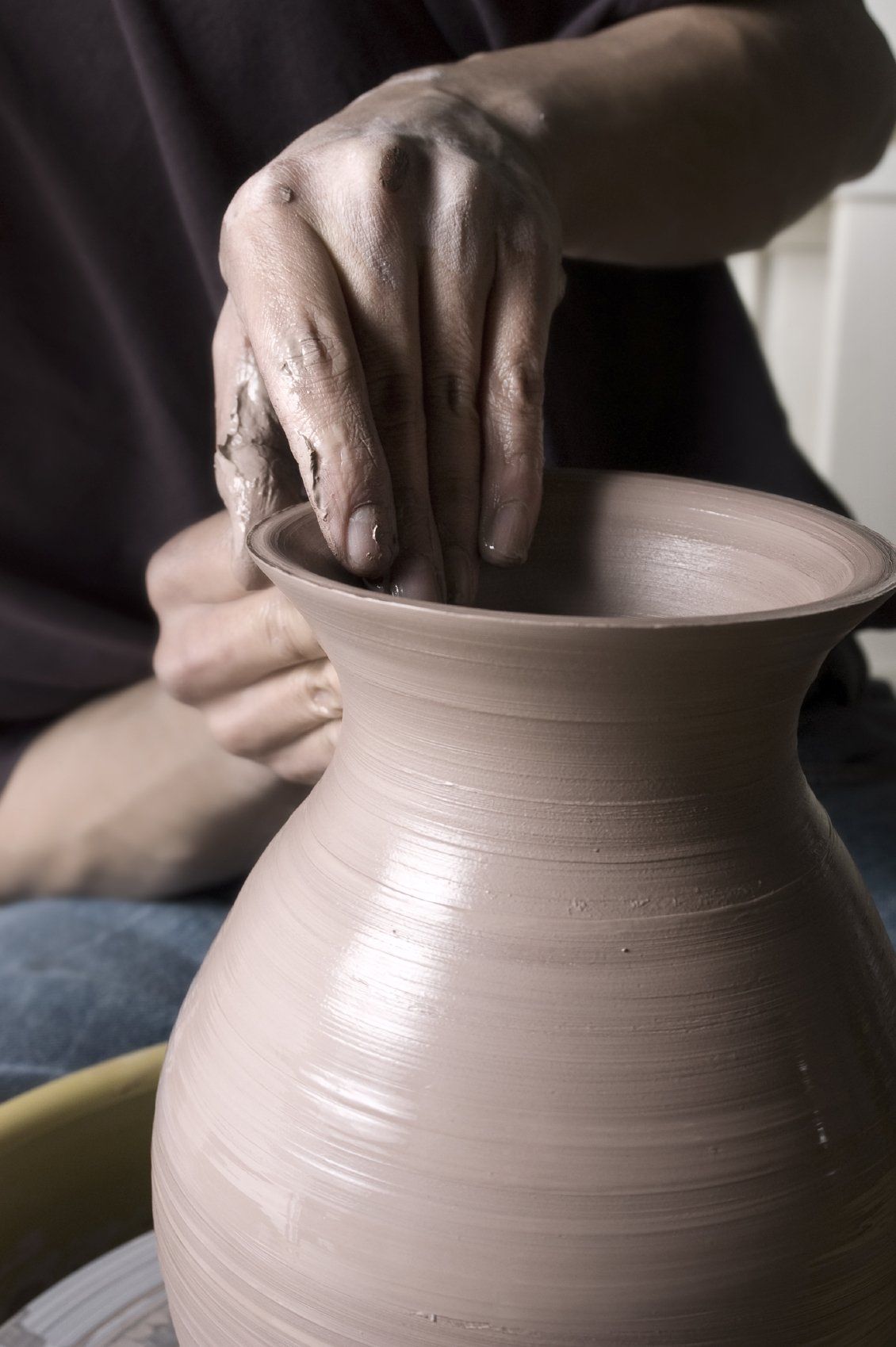 Zwei Hände beim Töpfern einer Vase