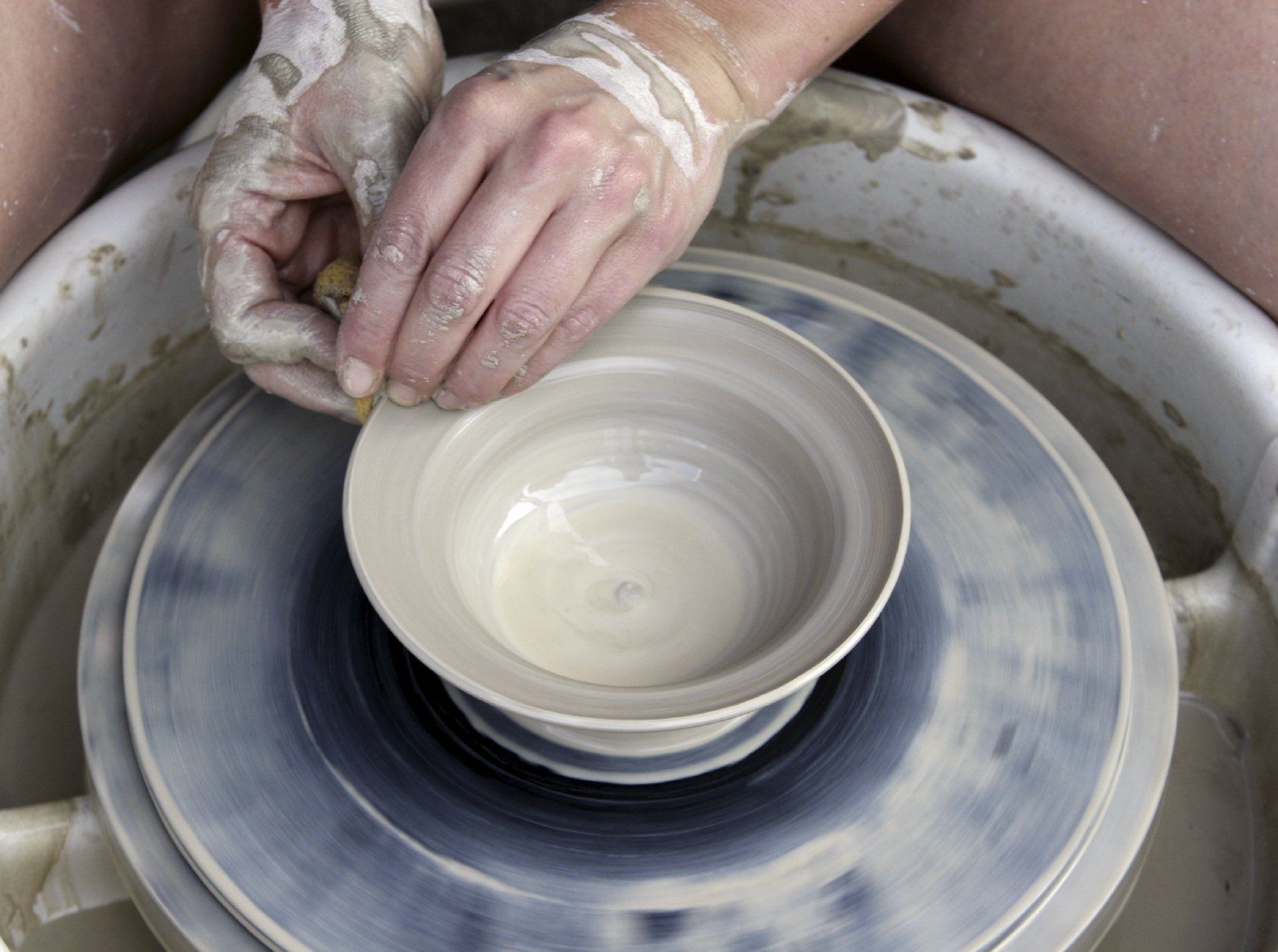 The hands of a woman moulding a piece of pottery.