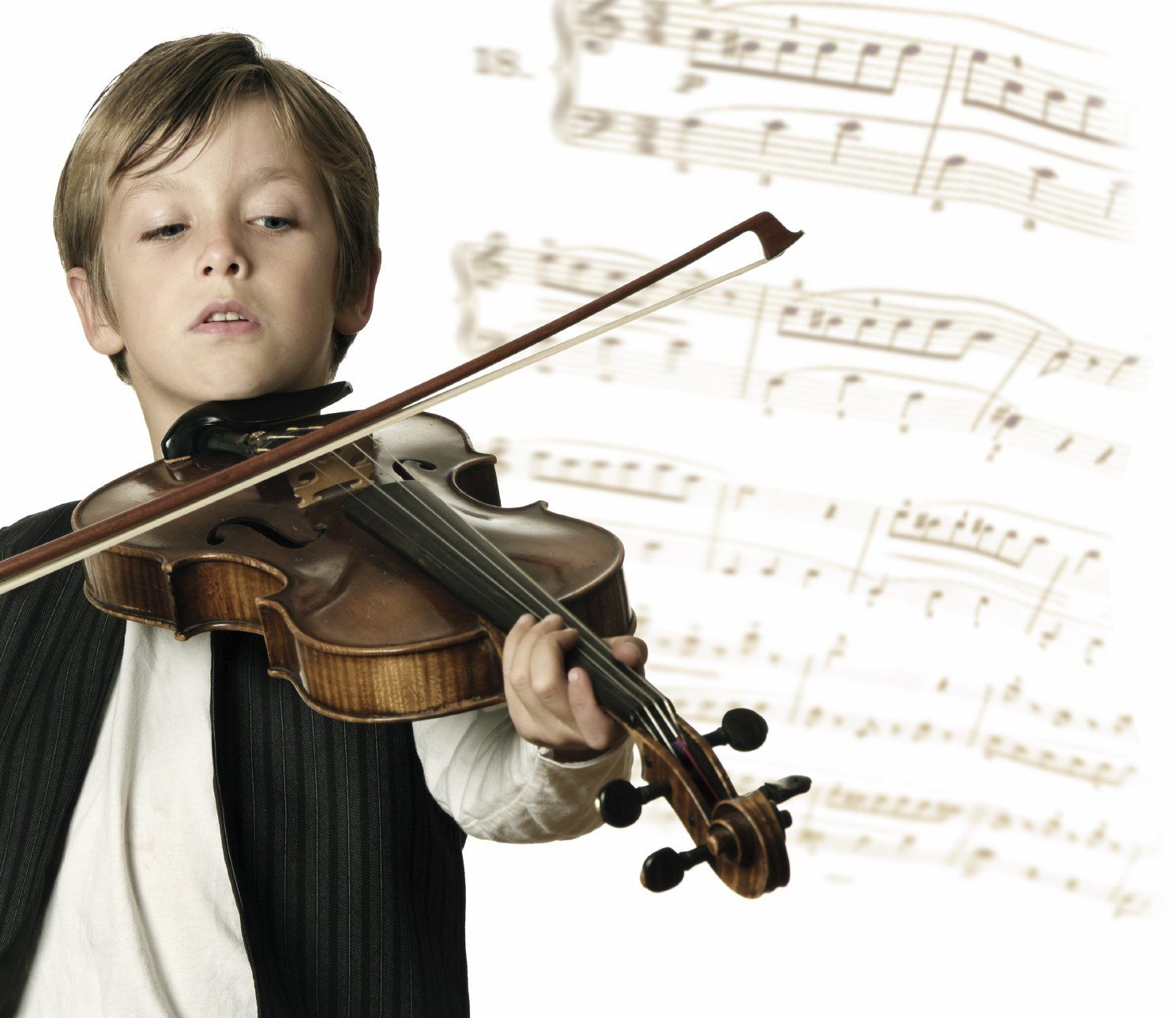 Young boy playing a violin; with music sheets in the background.