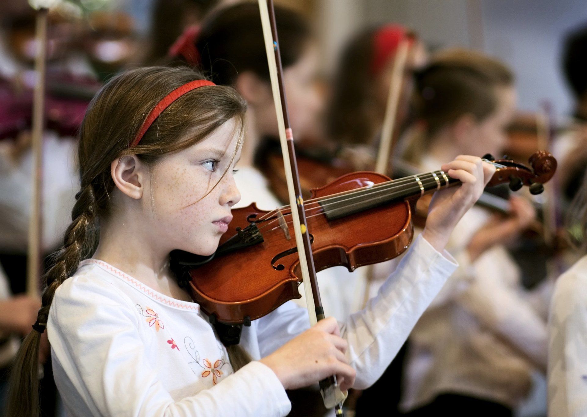 Young girl playing the violin in an orchestra.