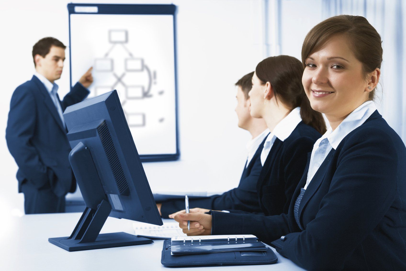 Three office workers in business suits, attending a lecture at work.