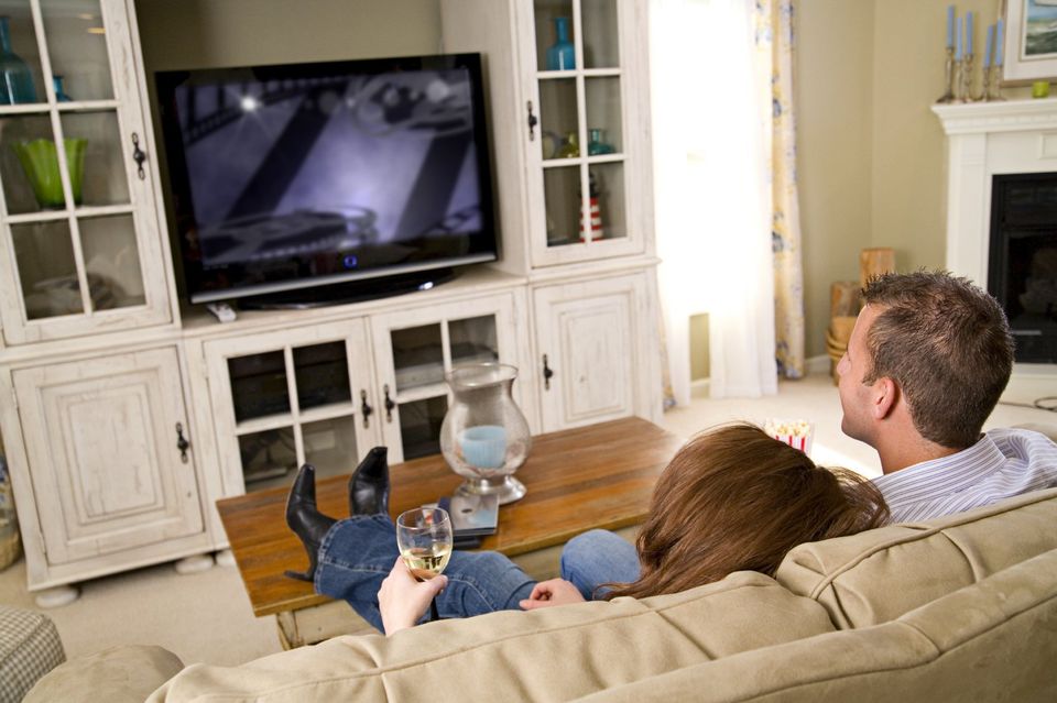 Couple watching t.v having  a glass of wine 