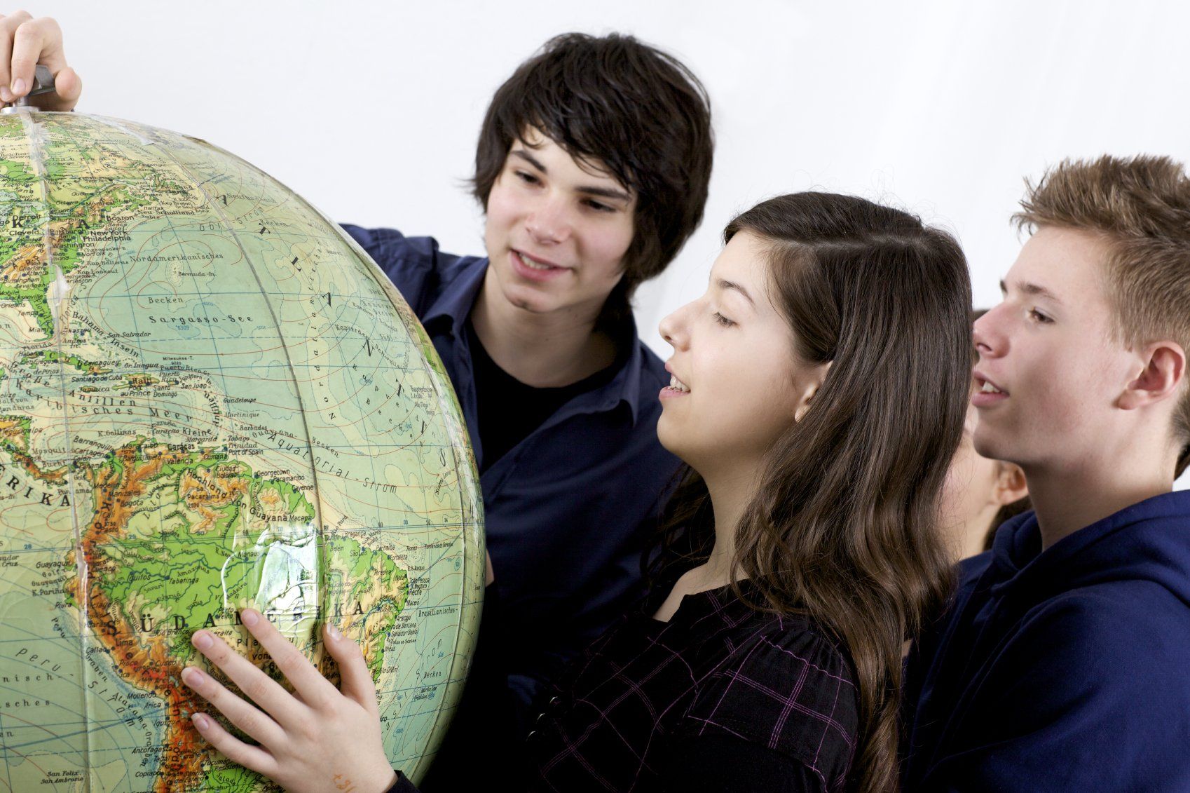 Three young students researching the countries of the world, on a globe.