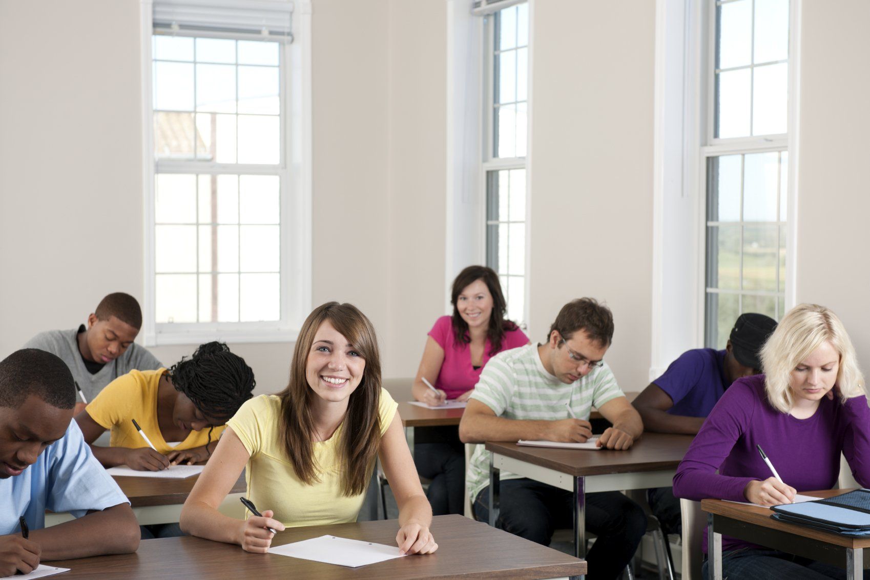 Eight students doing an exam in a classroom
