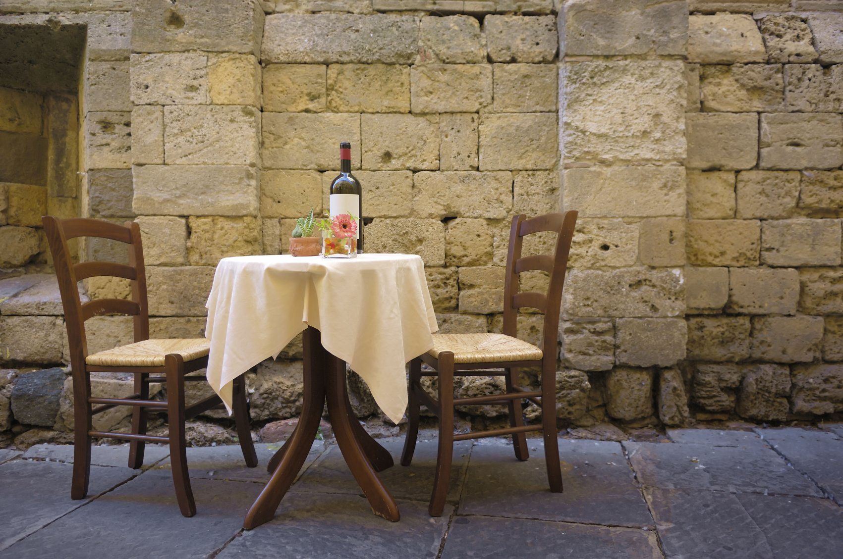 Tisch mit Wein und Blumen und zwei Stühlen