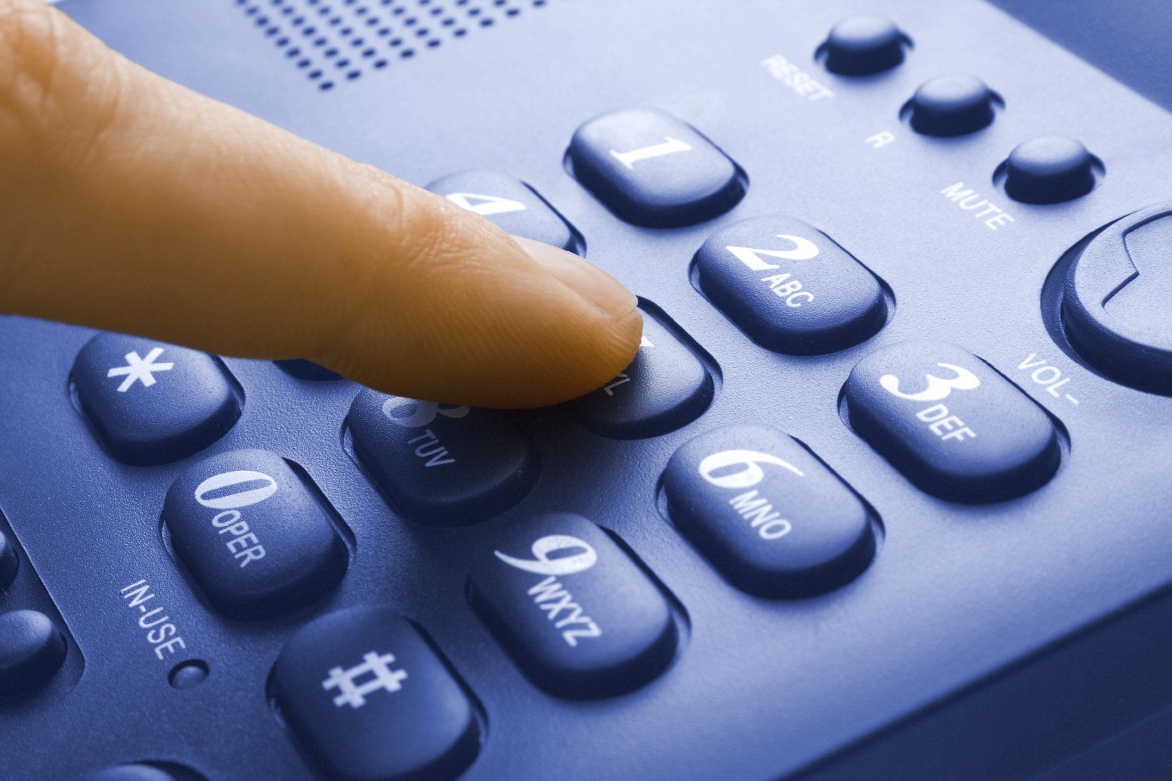 Finger einer Person, die eine Telefonnumer auf schwarzem Tastentelefon wählt