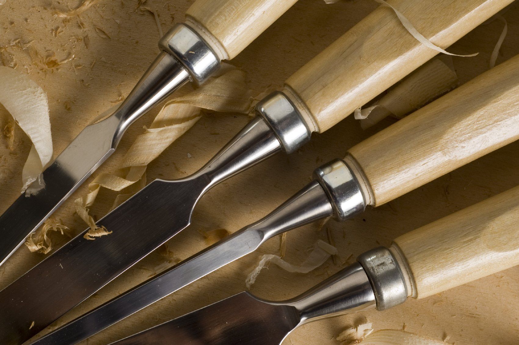 Four chisels sitting on a workbench.