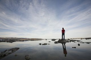 Eine Person steht auf einem Stein umgeben von Wasser