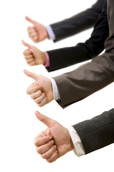 Four people's arms in business professional dress giving the thumbs-up