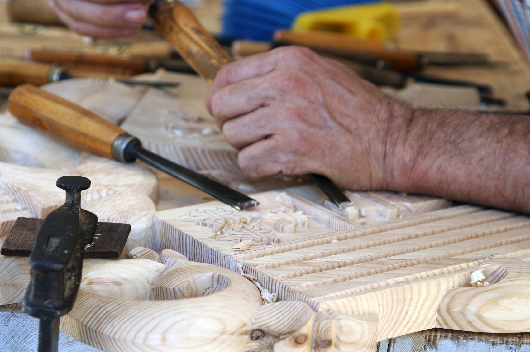 A woodworker carving a piece of wood  on his workbench