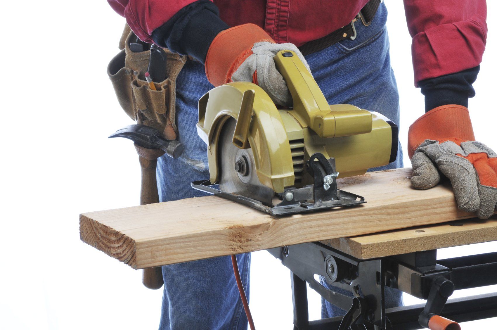 A workman wearing a tool belt and gloves, while cutting a piece of wood with a circular saw.