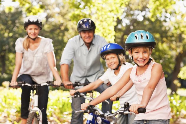 Das Bild zeigt eine Familie auf Fahrrädern mit Fahrradhelmen.